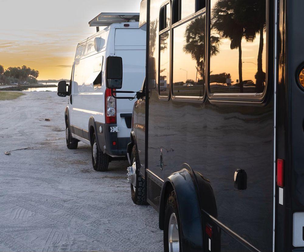 Reflective black trailer beside a work van after exterior care.